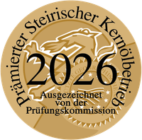 Goldenes Siegel mit '2026', 'Ausgezeichnet von der Prüfungskommission' und der Phrase 'Primärer Steirischer Kernölbetrieb'. Es enthält ein stilisiertes Design mit Sternen.
