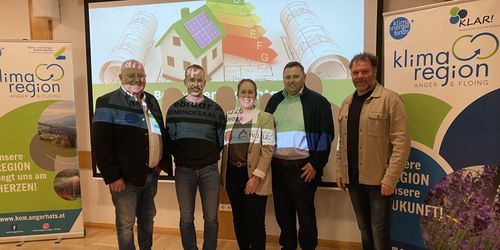 Fünf Personen posieren für ein Foto vor einer Projektionsleinwand, die ein Diagramm über Energieeffizienz zeigt.