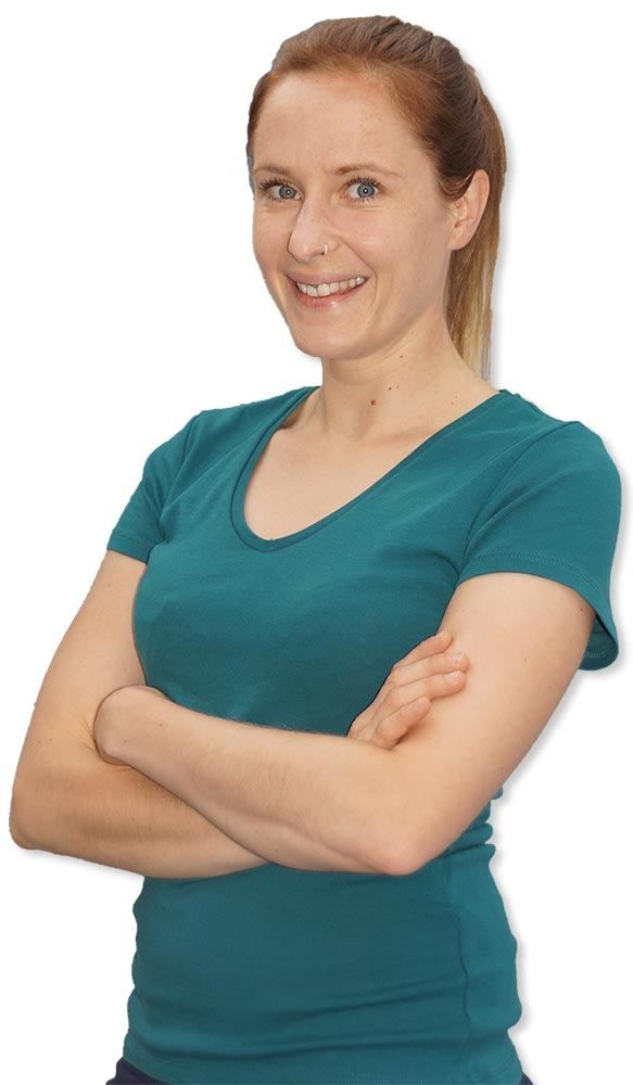 Eine lächelnde Frau mit grünem T-Shirt und verschränkten Armen posiert für ein Bild. Sie hat einen Nasenring.