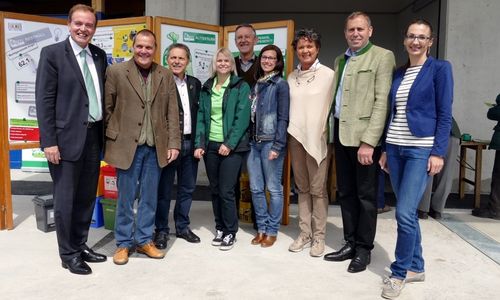 Eine Gruppe von Menschen steht nebeneinander vor einem Gebäude. Sie alle lächeln und posieren für ein Foto.