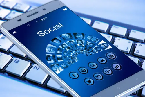 Ein Smartphone mit einer Social-Media-App auf dem Bildschirm. Die App zeigt eine Collage von Gesichtern und Symbole für verschiedene soziale Medien. Zeit ist 11:45 Uhr.