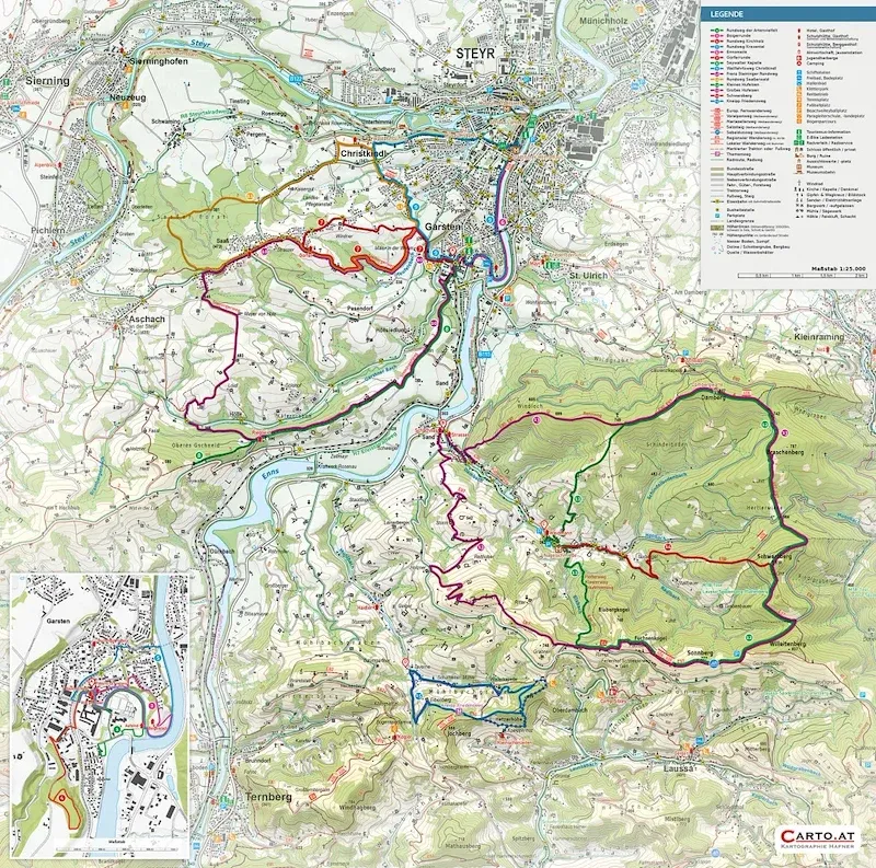 Eine Karte zeigt verschiedene Wanderwege mit unterschiedlich farbigen Linien auf einem grünen Hintergrund. Die Karte enthält eine Legende, die Namen von Orten und eine kleine eingebettete Karte in der unteren linken Ecke.