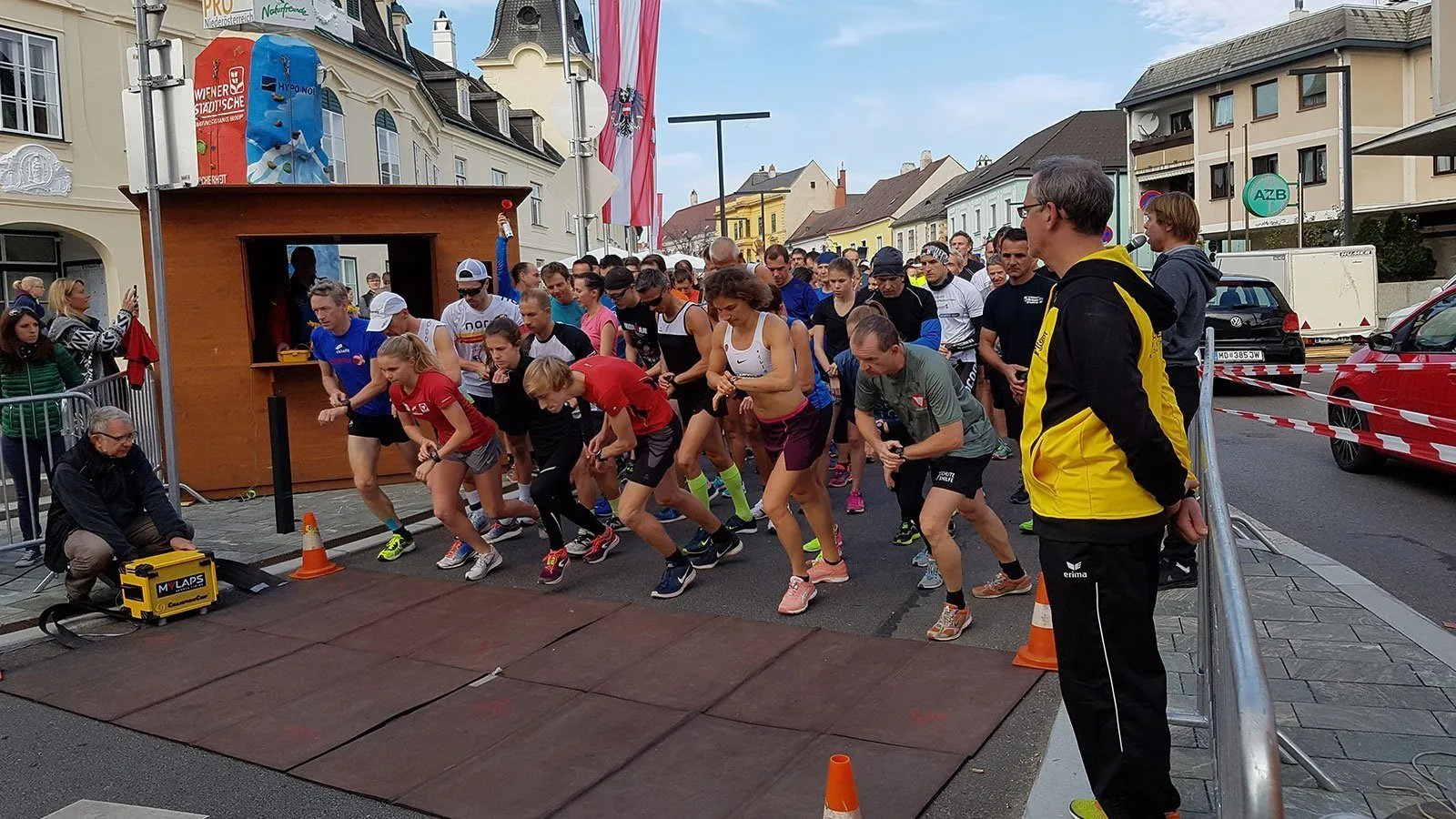 Ein Marathonrennen, Teilnehmer in verschiedenen Farben und Outfits laufen auf der Straße, mit einem Mann vorne und Gebäuden im Hintergrund.
