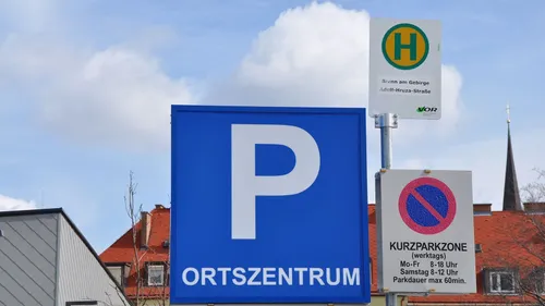 Ein blaues Schild mit einem weißen Buchstaben P und dem Wort Ortszentrum, mit einem Gebäude im Hintergrund.