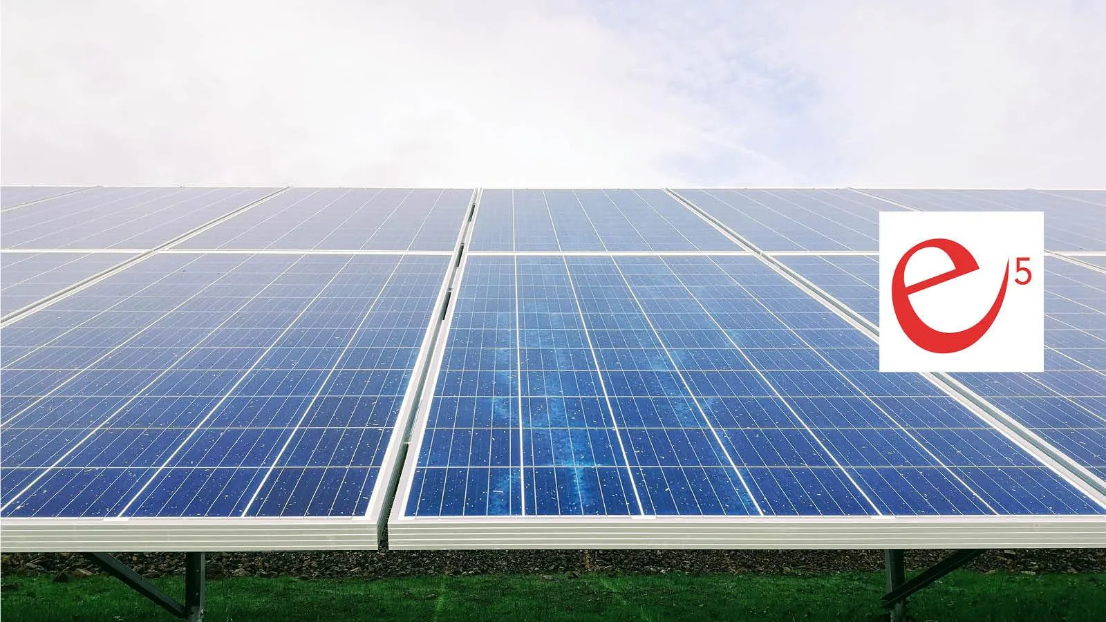 Eine Reihe von Solarpanelen, die am Boden installiert sind und Sonnenlicht bei teilweise bewölktem Himmel einfangen.