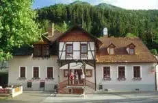 Ein traditionelles weißes Gebäude mit braunem Dach und Fenstern, eingebettet vor einem üppigen grünen Wald.