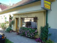Ein Laden mit dem Namen Fleischhauerei, ein gelbes Gebäude mit Blumen, ein Schild über dem Eingang und ein Lieferwagen im Fenster reflektiert.