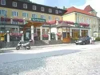 Ein Auto und ein Roller sind auf der Straßenseite vor einem Gebäude mit Blumen und einem Schild geparkt.