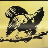 Eine schwarze Silhouette eines Hahns auf einem Ast vor gelbem Hintergrund.