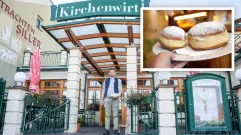 Ein Mann steht vor einem Restaurant namens 'Kirchenwirt' und hält eine Platte mit Donuts. Das Restaurant hat ein hölzernes Vordach und ein Schild über dem Eingang.
