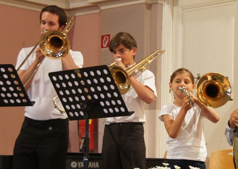 Bild enthält, Person, Child, Female, Girl, Musical Instrument, Horn, Trumpet, Group Performance, Face, Musician