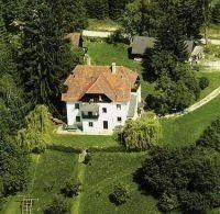 Ein Luftbild eines großen weißen Hauses mit einem braunen Dach, umgeben von saftigem grünem Laub und Gras in einer ländlichen Gegend.