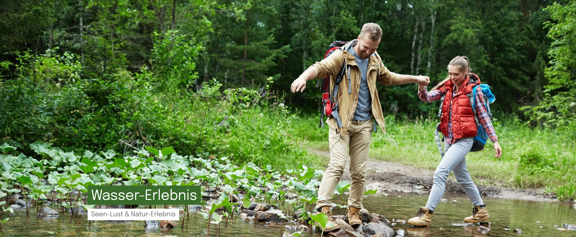 Ein Mann mit Rucksack und Wanderschuhen geht über einen Bach. Er lächelt und scheint die Natur zu genießen.