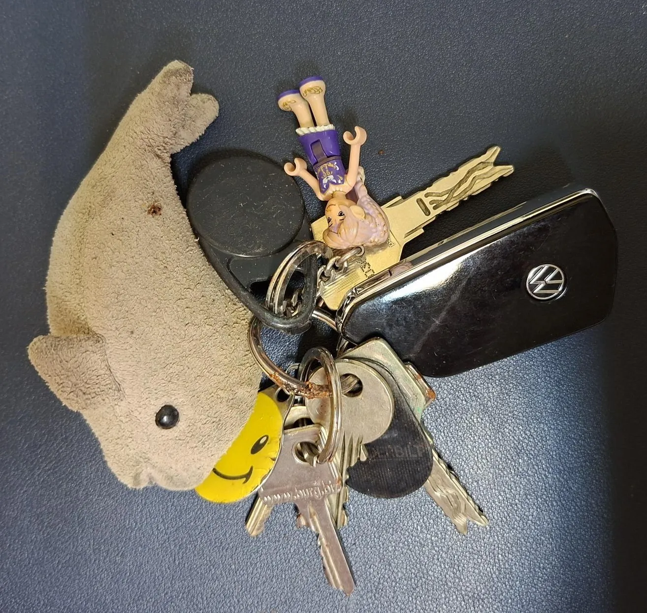 Eine Sammlung von Schlüsseln und einem Plüschtier auf einer dunklen Oberfläche.