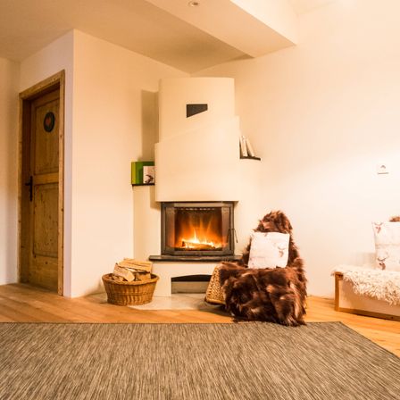 Ein modernes Wohnzimmer mit einem Kamin, einem Korb mit Holz und einem Teppich auf dem Boden.