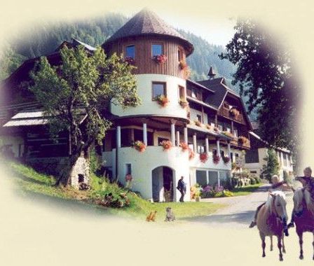 Zwei Personen reiten Pferde vor einem Hotel mit einem runden Turm und vielen Fenstern.