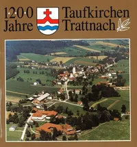 Luftaufnahme des Dorfes Taufkirchen Trattnach. Viele Gebäude und Häuser, einschließlich einer Kirche, sind in einer grünen Landschaft zu sehen. Das Datum 1200 Jahre ist prominent angezeigt.