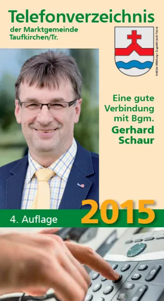 Ein Plakat, das die 2015er Ausgabe des Telefonverzeichnis der Marktgemeinde Taufkirchen/Tr bewirbt. Das Plakat zeigt einen Mann mit Brille und gelber Krawatte, der lächelt. Der Text lautet 'Eine gute Verbindung mit Bgm. Gerhard Schaur'. Unten hat eine Hand einen Telefonknopf gedrückt.