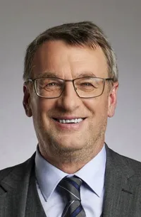 Ein lächelnder Mann mit Brille und Businessanzug.