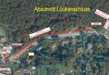 Eine Luftaufnahme eines Ortes namens Luckenschluss. Es zeigt eine Straße, mehrere Häuser und einen Wald. Es gibt mehrere beschriftete Linien und Kästen, die bestimmte Bereiche kennzeichnen.