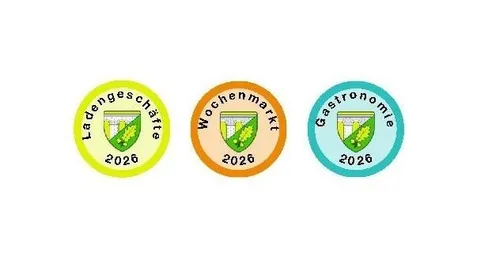 Drei runde Logos in Gelb, Orange und Blau. Jedes Logo enthält ein Emblem und das Jahr 2026. Das linke Logo sagt 'Ladengeschäfte', das mittlere 'Wochenmarkt' und das rechte 'Gastronomie'.
