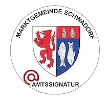 Das Logo für 'Marktgemeinde Schwadorf' zeigt einen Schild mit einem roten Löwen, zwei silbernen Fischen und einem roten und weißen Hintergrund. 'Amtsssnatur' steht in Rot unter dem Schild.