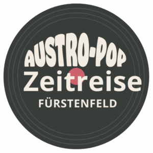 Ein kreisförmiges Logo mit dem Text 'ASTRO-POP Zeitreise' in weißer Schrift, zentriert auf schwarzem Hintergrund. Unter dem Haupttext befindet sich der kleinere Text 'Fürstenfeld'. Das Logo ist so gestaltet, dass es einer Schallplatte ähnelt.