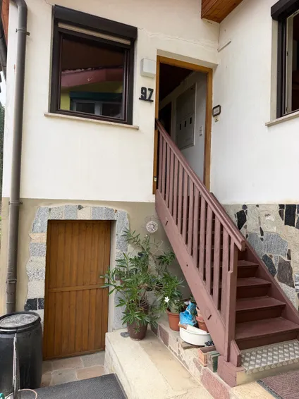 Der Eingang eines Hauses mit einer Holztür und einer Treppe, die zur Tür führt.