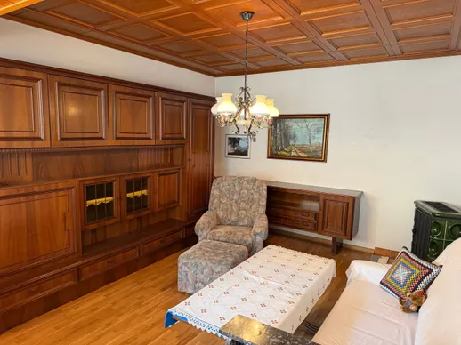 Ein Wohnzimmer mit Holzmöbeln, einer Kronleuchter und einem Gemälde an der Wand.