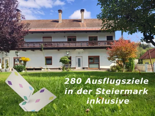 Ein weißes Haus mit zwei Schornsteinen und einem Balkon vor einem Rasenbereich. Der Text lautet 280 Ausflugsziel in der Steiermark inklusive.