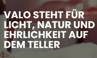 Ein weißer Text auf einem unscharfen Hintergrund lautet 'VALO STEHT FÜR LICHT, NATUR UND EHRLICHKEIT AUF DEM TELLER'.