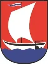 Das Emblem zeigt ein Segelboot auf rotem und blauem Hintergrund. Das Segelboot hat eine weiße Segel und eine kleine Flagge auf seinem Mast. Das Wasser unter dem Boot ist blau.
