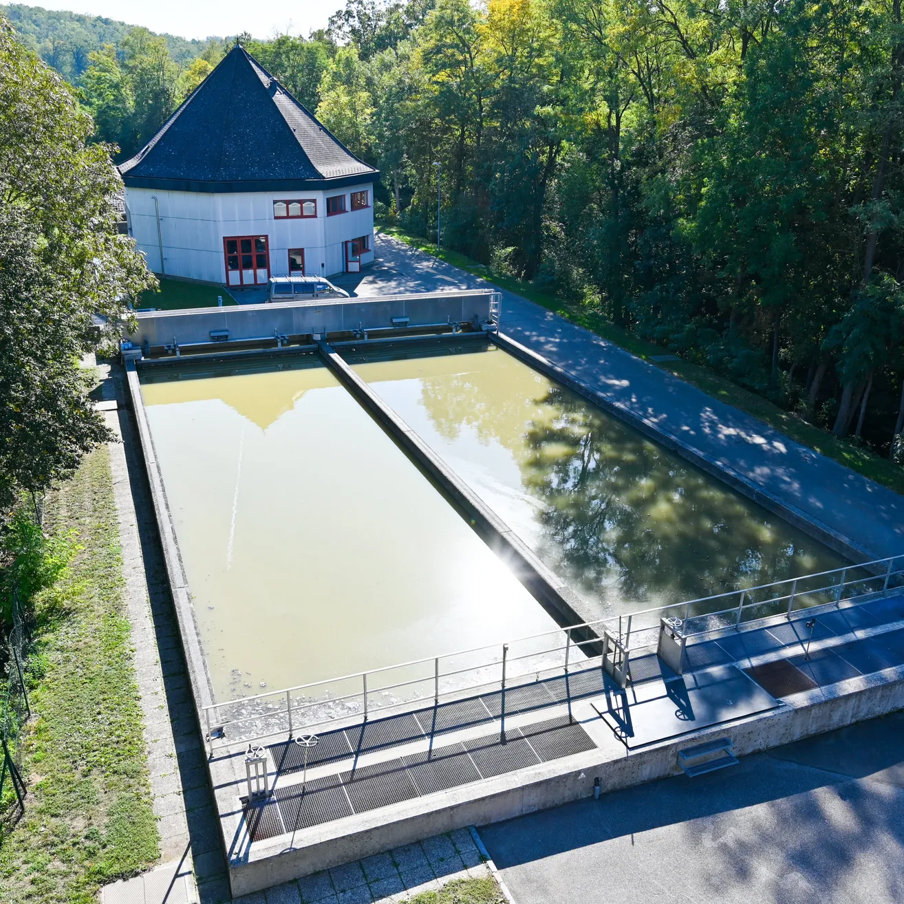 Eine Luftaufnahme einer Wasseraufbereitungsanlage mit einem großen Wasserbecken und einem Gebäude im Hintergrund.