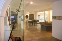 Ein Museumskorridor zeigt verschiedene Gegenstände. Links steht eine große Lanze und rechts ein Tisch mit einem Stadtmodell.