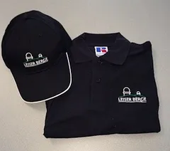 Ein schwarzes Polohemd und eine schwarze Baseballkappe mit weißem Rand und einem Logo, das 'LEISER BERGE' liest, werden auf einer weißen Oberfläche angezeigt.