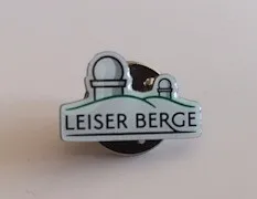 Ein Anstecknadel mit einem Teleskop auf einem Hügel und den Worten 'LEISER BERGE' darunter geschrieben.