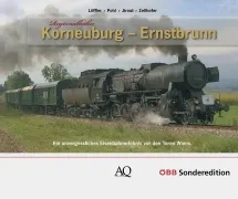 Eine schwarze Dampflokomotive zieht einen Zug durch ein Grasfeld mit Bäumen im Hintergrund.