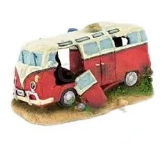 Ein Miniatur-Modell eines roten und weißen Volkswagen-Camper-Vans ist auf einer Grasfläche kaputt.