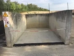 Eine Betonstruktur mit einem gelben Schild und einer roten und weißen Seilbarriere.