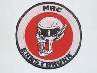 Ein rundes Abzeichen mit rotem Hintergrund und weißem Rand. In der Mitte befindet sich ein Schädel mit schwarzem Visier und Blitzen. Das Abzeichen hat den Text 'EINSTBRUNN' in Schwarz am unteren Rand und 'MRC' in Schwarz oben.