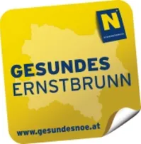 Ein gelber Aufkleber mit einer Karte einer Region im Hintergrund und dem Text 'GESUNDES ERNSTBRUNN' in blauer Schrift.