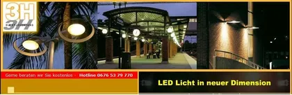 Eine Nachtszene eines Bahnhofs mit LED-Beleuchtung. Der Bahnhof hat einen überdachten Gehweg mit Straßenlampen und einem Mülleimer.