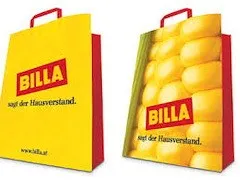 Zwei gelbe und rote Papiertüten mit dem Wort BILLA darauf. Die linke Tüte hat einen roten Griff und ein Bild von einem Maiskolben auf der Seite. Die rechte Tüte hat einen roten Griff und ein Bild von einem Haufen Maiskolben auf der Seite.