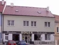 Ein Gebäude mit rotem Dach und weißen Wänden, beschriftet mit 'HOGER', mit zwei Autos davor geparkt.