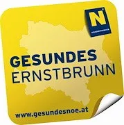 Ein gelbes quadratisches Aufkleber mit einer Karte einer Region namens Ernstbrunn auf Deutsch. Die Karte ist in hellbrauner Farbe hervorgehoben. Der Aufkleber enthält auch den Text 'www.gesundesnoe.at' und ein Logo mit dem Buchstaben 'N'.