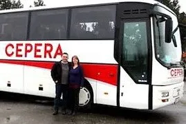 Ein Mann und eine Frau stehen vor einem weiß-roten Bus mit der Aufschrift 'CEPERA'.