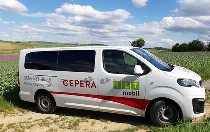 Ein weißer Van mit rotem Rand steht auf einem Feld.