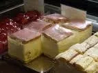 Eine Vitrine mit mehreren Kuchenscheiben, jede mit einer Schicht rosa Glasur gekrönt.