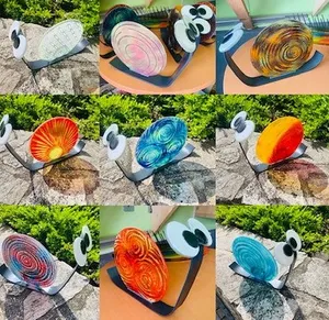 Eine Collage von neun Glasschneckenskulpturen, jede mit einem anderen farbenfrohen Spiralmuster, auf einem Steinuntergrund und einem Holztisch ausgestellt.