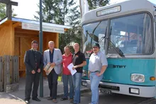 Fünf Männer stehen vor einem blau-weißen Bus.